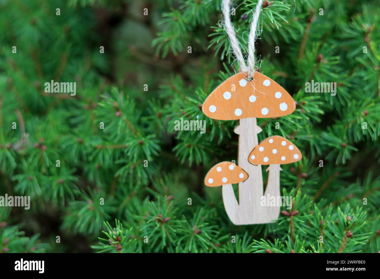 Holzspielzeugpilze auf den Zweigen eines Weihnachtsbaums. Handgemachte umweltfreundliche Urlaubsdekoration. Stockfoto