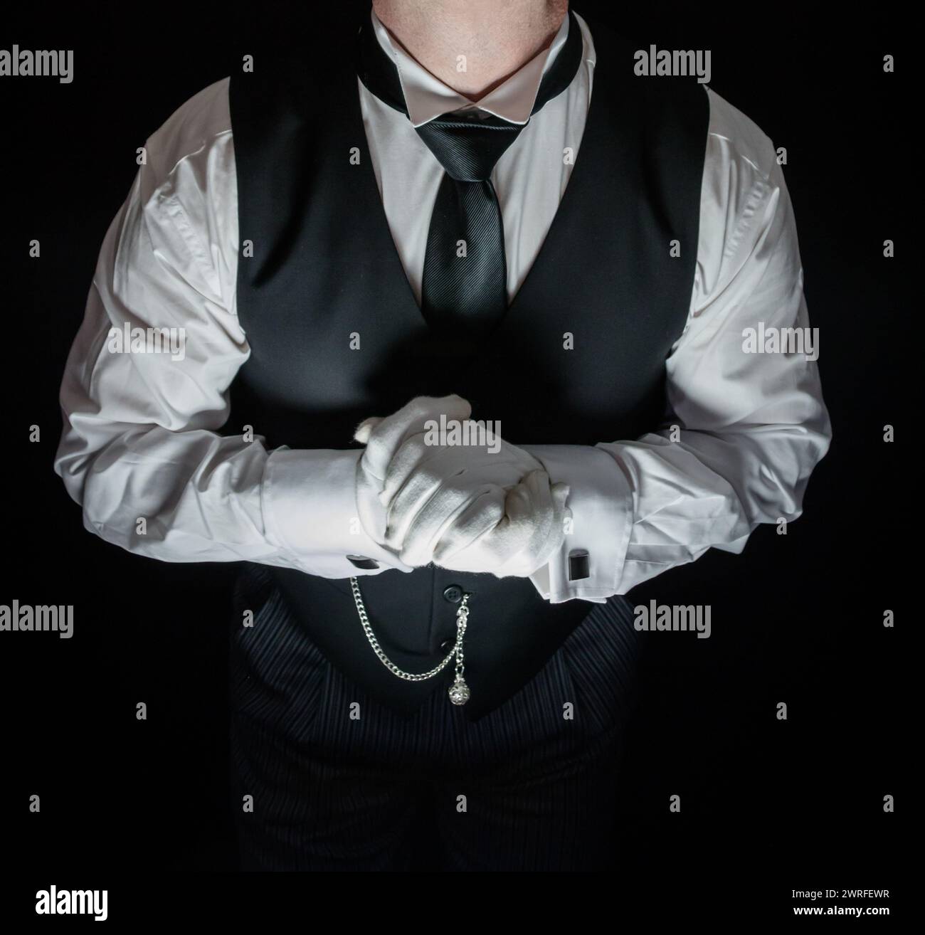 Porträt von Butler in dunklem Anzug und weißen Handschuhen, die gerne zu Diensten sein möchten. Konzept der Dienstleistungsbranche und des professionellen Gastgewerbes. Stockfoto