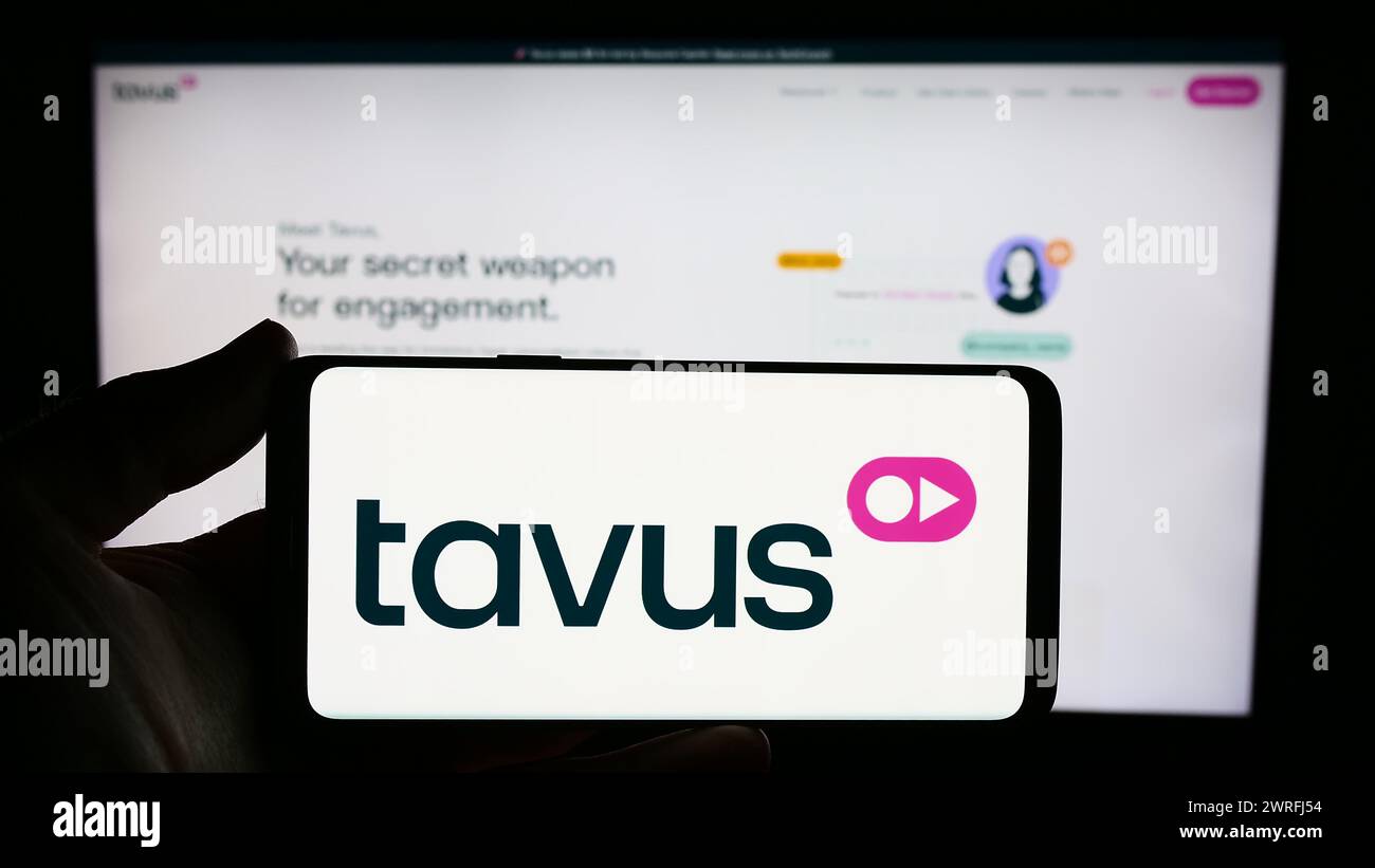 Person mit Smartphone und Logo des US-amerikanischen Videounternehmens Tavus Inc. Vor der Website. Schwerpunkt auf dem Display des Telefons. Stockfoto