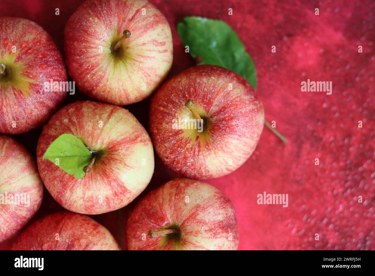 Rote Äpfel mit Blättern auf rotem Hintergrund. Draufsicht, flach Stockfoto