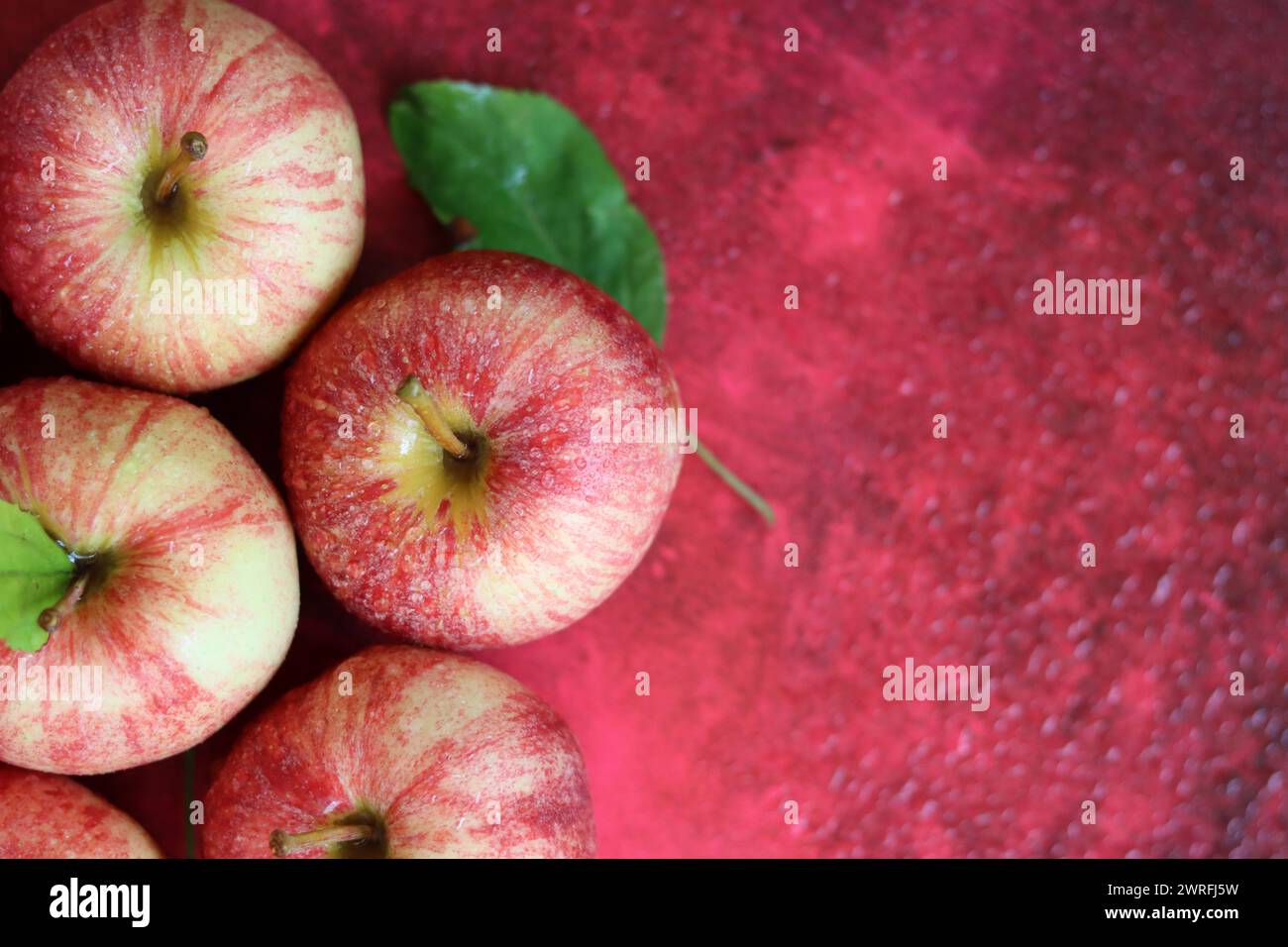 Rote Äpfel mit Blättern auf rotem Hintergrund. Draufsicht, flach Stockfoto