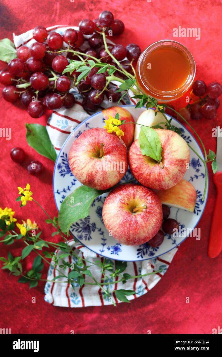 Lebendiges Stillleben mit Trauben und Äpfeln auf strukturiertem rotem Hintergrund mit Platz für Text. Konzept für gesunde Ernährung. Stockfoto