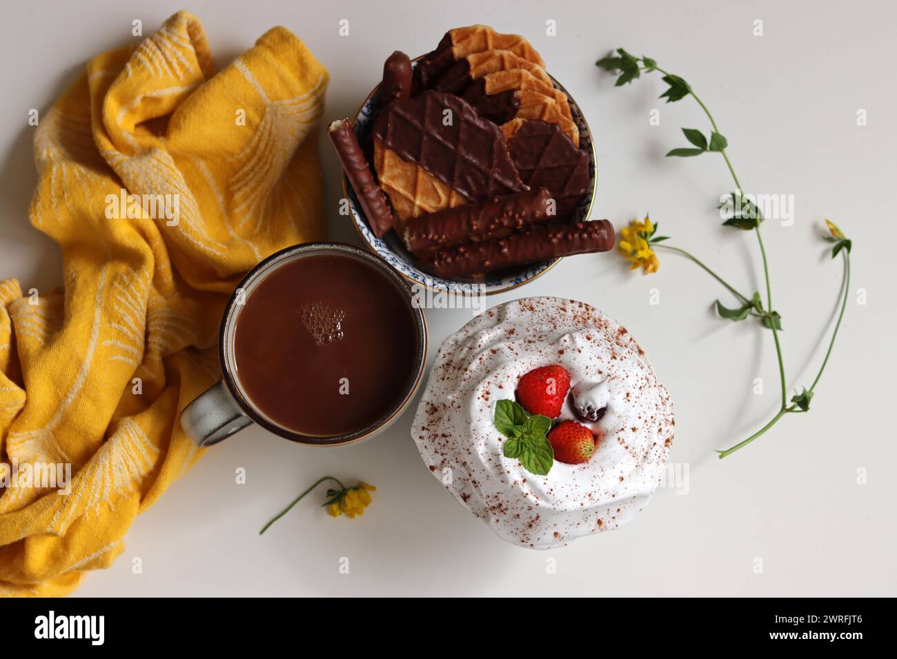 Foto von oben mit einer Tasse Milchtee, Waffeln und Keksen in einer Schüssel. Süßes Essen Nahaufnahme Foto. Weißer Hintergrund mit Leerzeichen für Text. Stockfoto