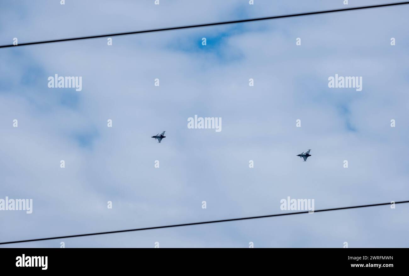Zwei Kampfflugzeuge fliegen in Formation gegen einen bewölkten Himmel, durchkreuzt von Stromleitungen, über Budapest Ungarn Stockfoto