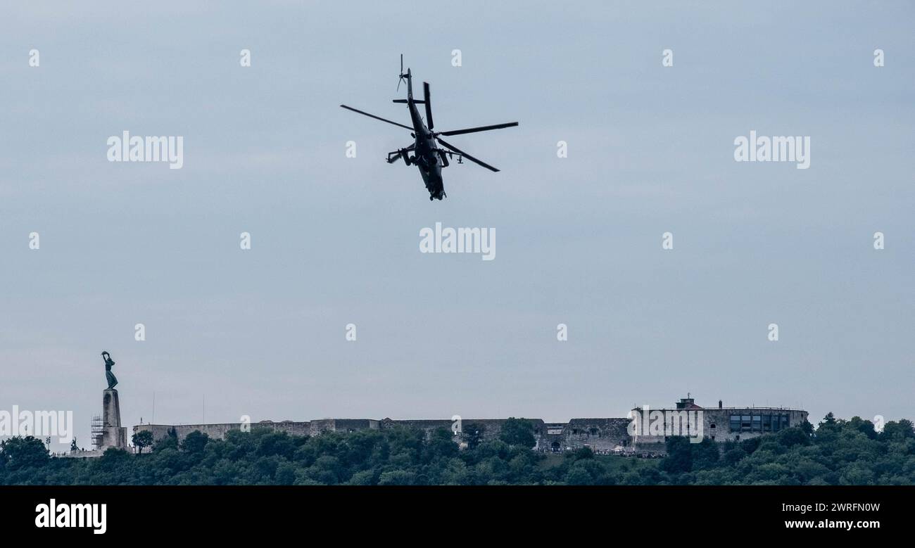 Militärhubschrauber fliegen über eine Skyline der Stadt mit einer historischen Statue im Vordergrund in Budapest Stockfoto