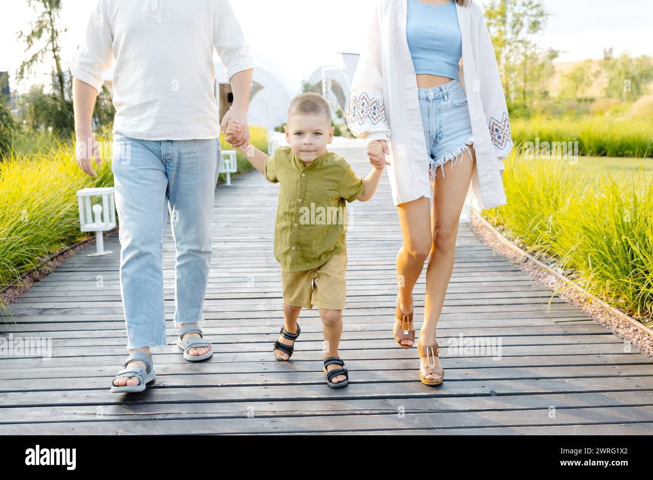 Ein Mann und eine Frau gehen mit ihrem kleinen Kind draußen. Die Familie macht einen gemeinsamen Spaziergang. Stockfoto