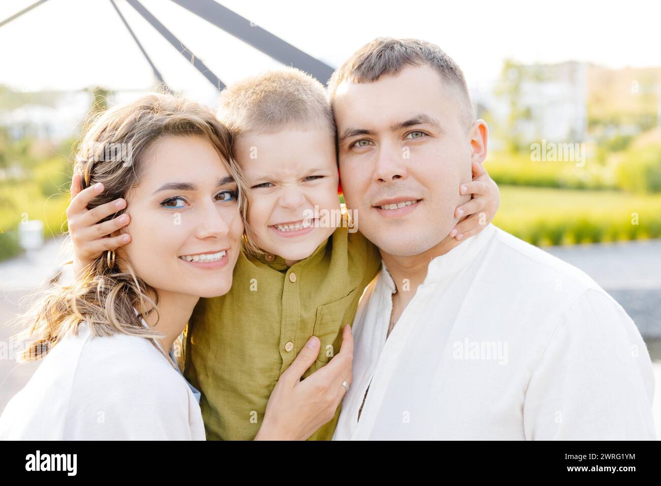 Ein Mann, eine Frau und ein Kind posieren zusammen und lächeln vor der Kamera für ein Familienporträt. Stockfoto