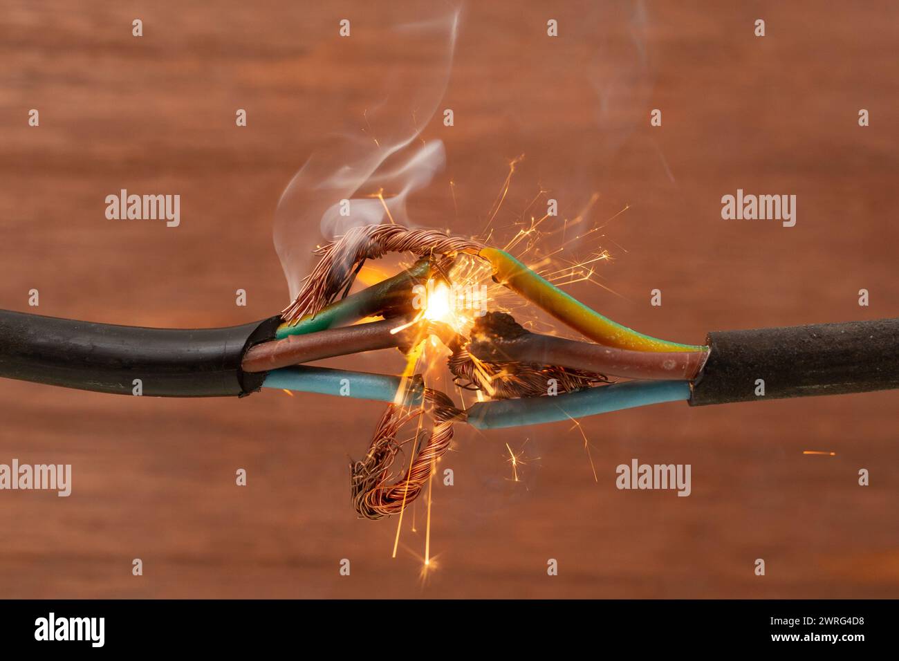 Funkenexplosion zwischen Elektrokabeln, auf braunem Holzhintergrund, Brandschutzkonzept Stockfoto