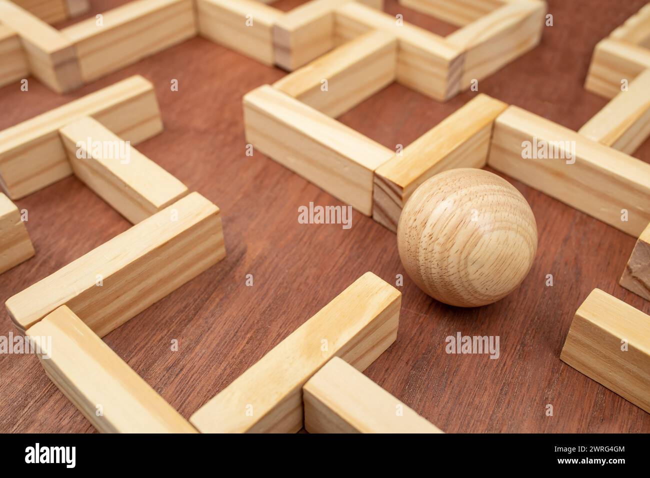 Holzlabyrinth aus Holzblöcken und einer Holzkugel, das ein Konzept für einen Ausweg aus dem Labyrinth findet Stockfoto