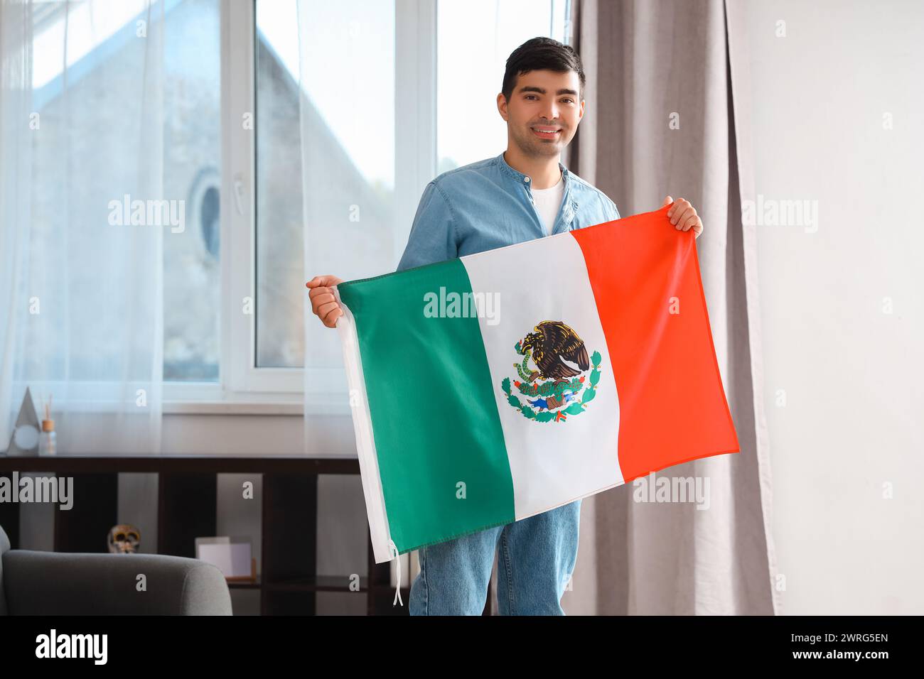 Junger Mann mit mexikanischer Flagge zu Hause Stockfoto