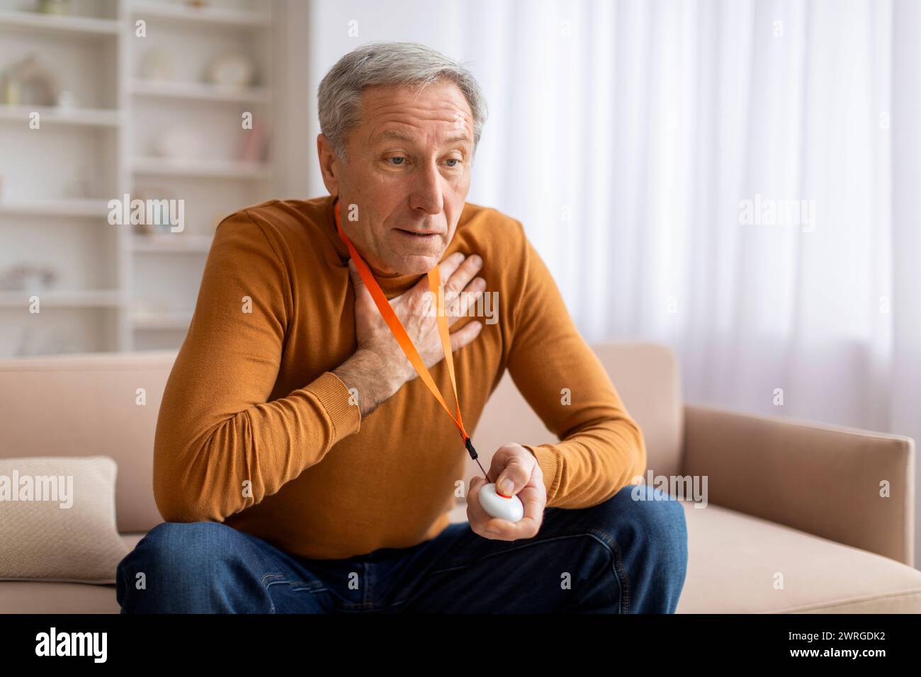 Ängstlicher, kranker Seniorenmann, der Panikknopf an der Notfallausrüstung drückt Stockfoto