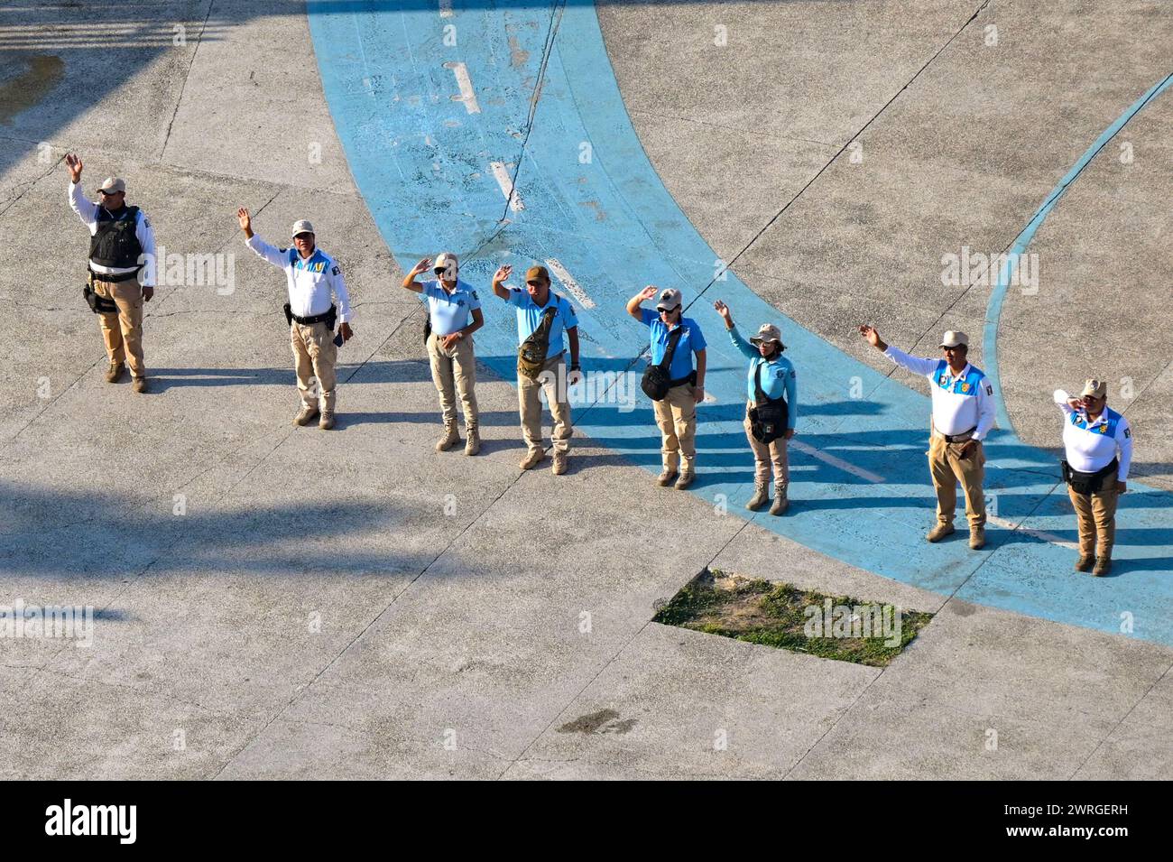 Acapulco, Mexiko - 17. Januar 2024: Reiseleiter am Hafen winken den Passagieren auf einem abfahrenden Kreuzfahrtschiff zu Stockfoto