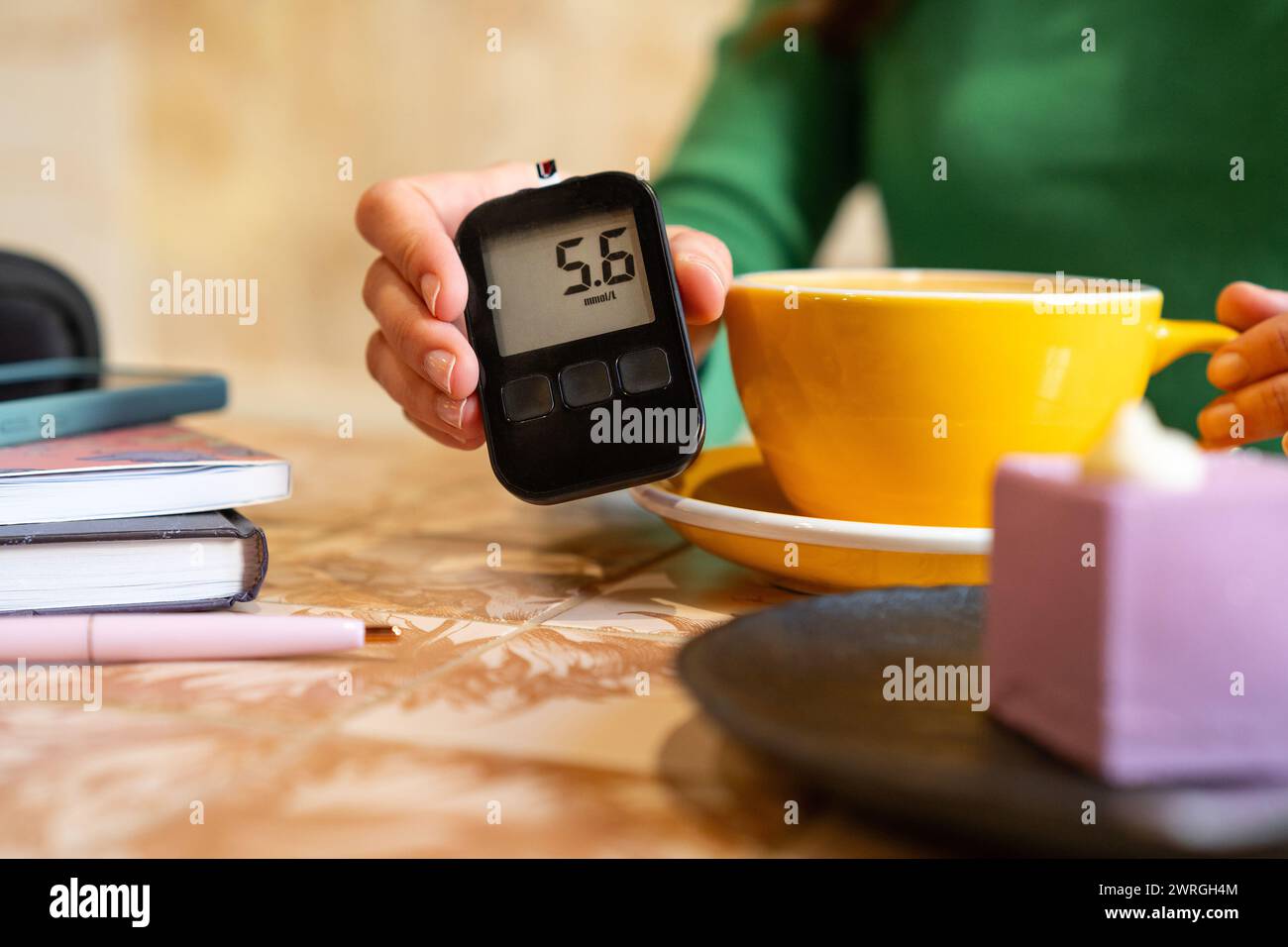 Diabetikerin, die an einem Tisch sitzt und in einem Café den Blutzuckerspiegel überprüft Stockfoto