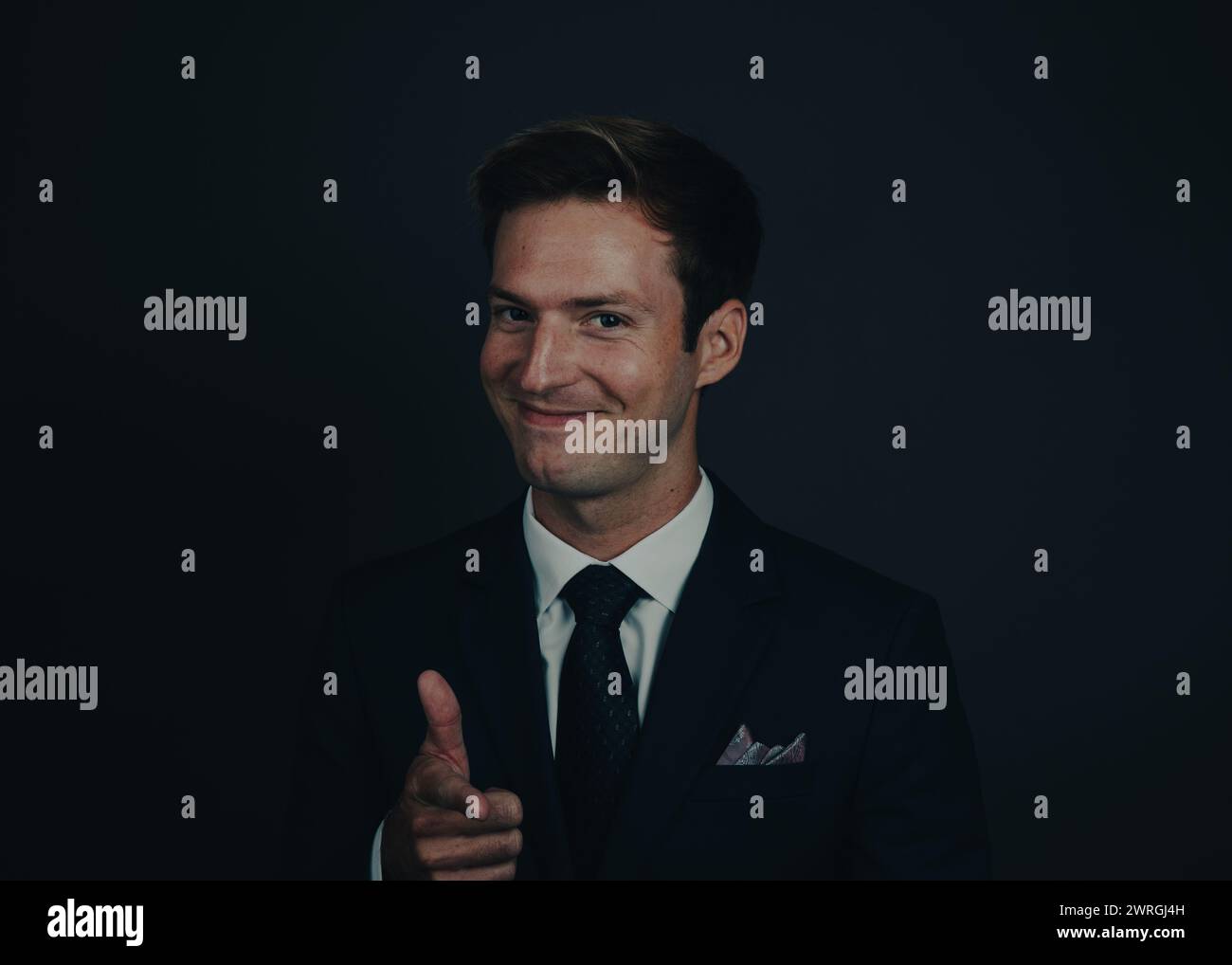 Nahporträt eines lächelnden Geschäftsmannes in einem Anzug, der zeigt Stockfoto