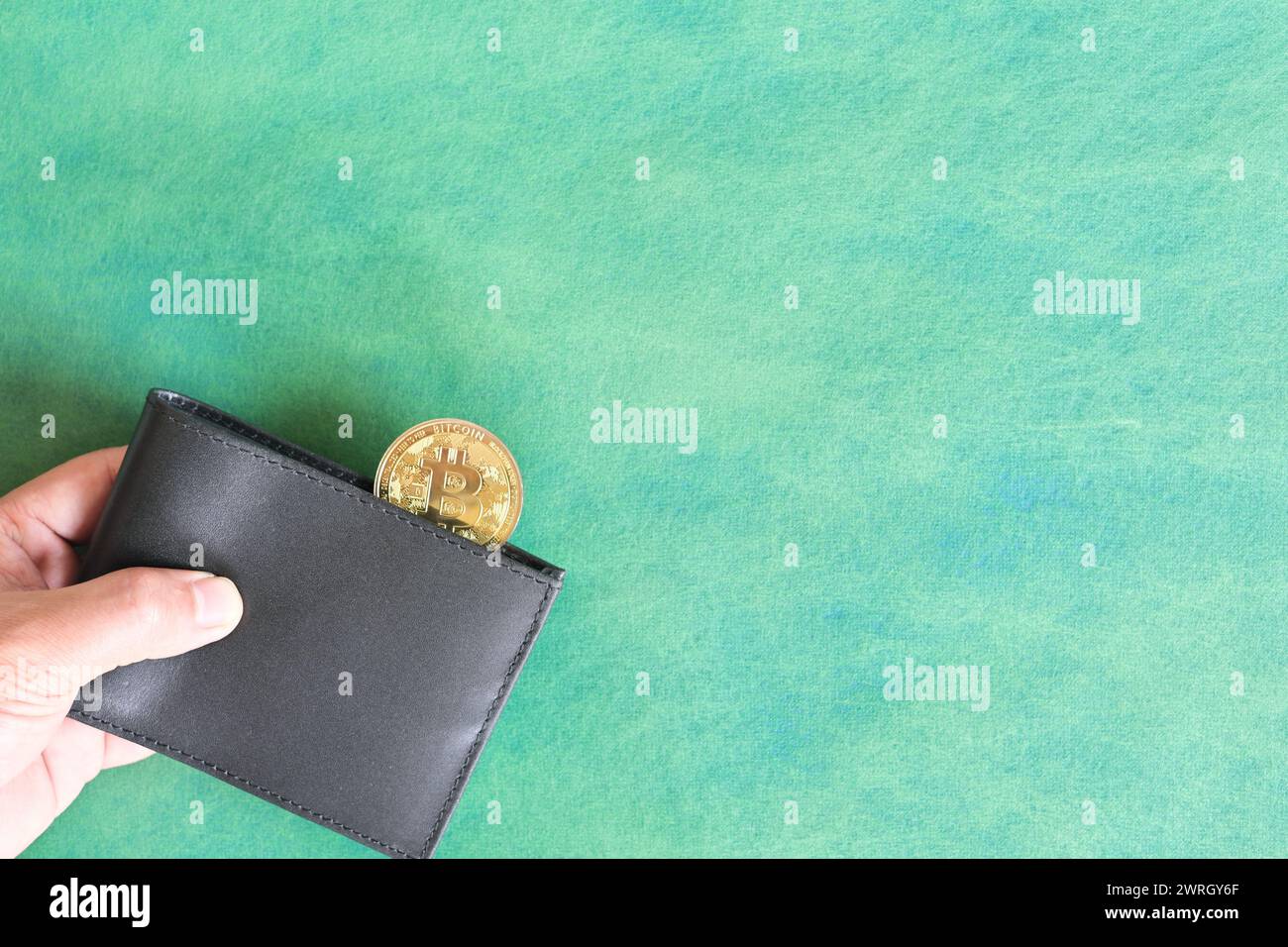 Menschliche Hand, die schwarze Brieftasche mit Bitcoin-Münze hält. Kryptowährung für Zahlungskonzept. Stockfoto