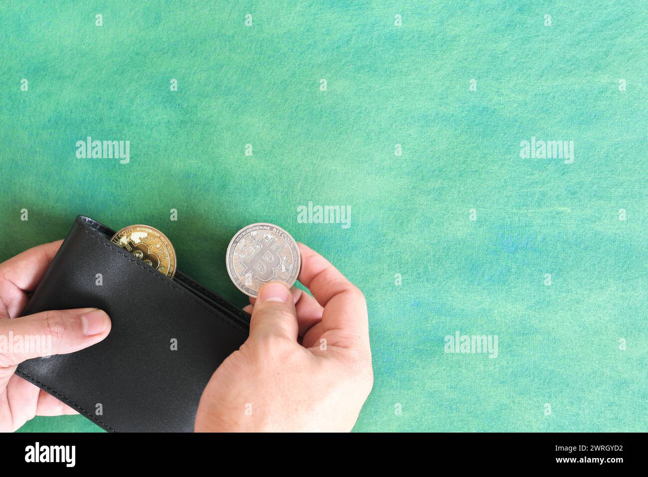 Menschliche Hand, die schwarze Brieftasche mit Bitcoin-Münze hält. Kryptowährung für Zahlungskonzept. Stockfoto