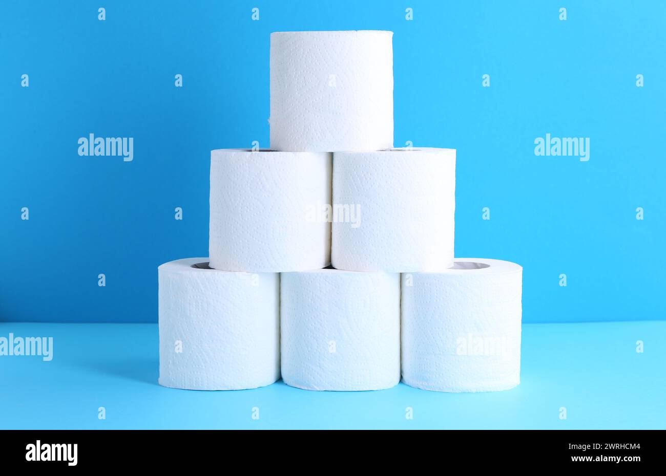 Pyramide aus Toilettenpapierrollen auf hellblauem Hintergrund Stockfoto