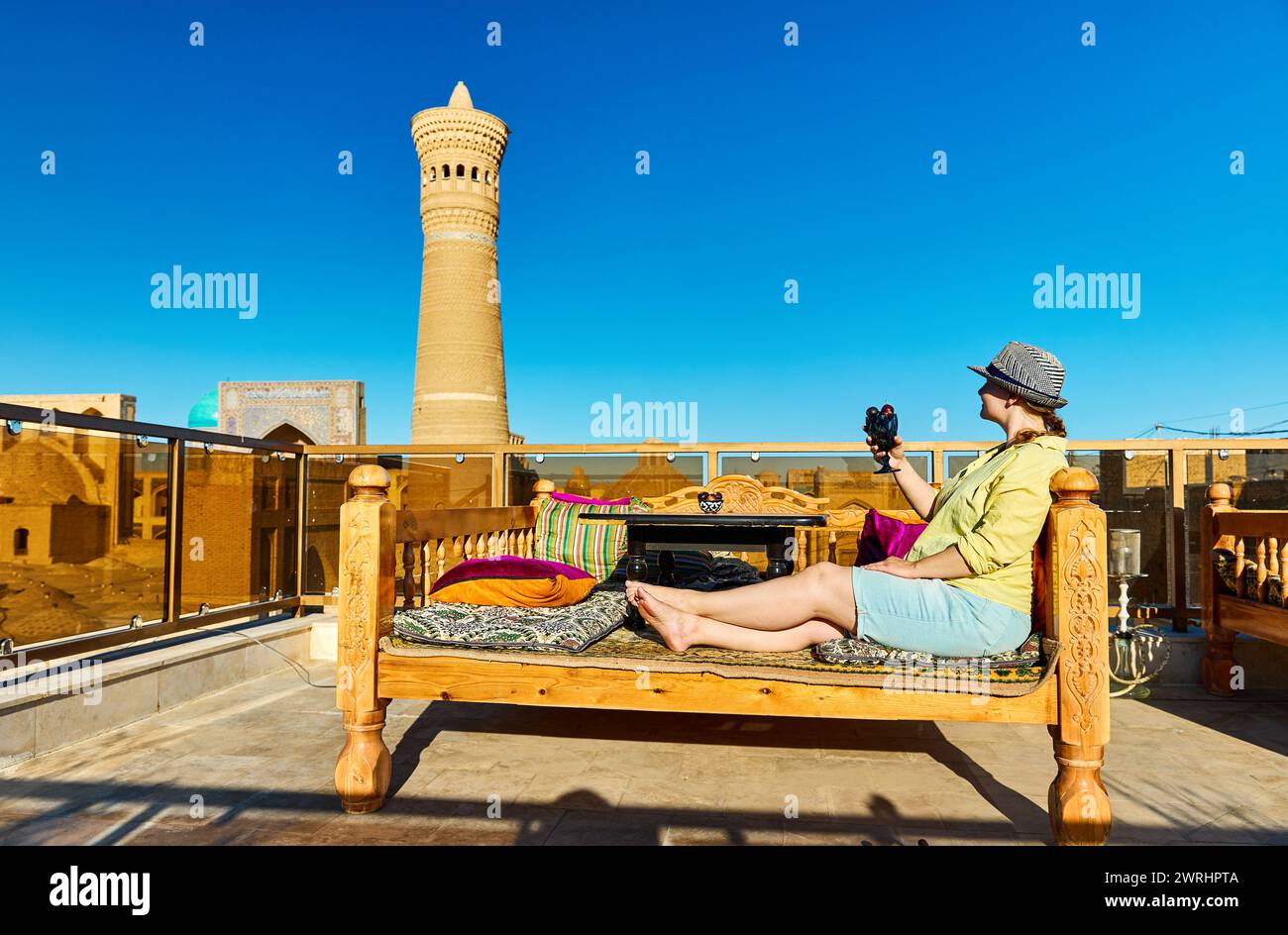 Frau mit Klasse voller Feigen am Tischbett Topchan im Dachrestaurant in Buchara in der Nähe des Kalyan Minarets und der Madrasah in Usbekistan Stockfoto