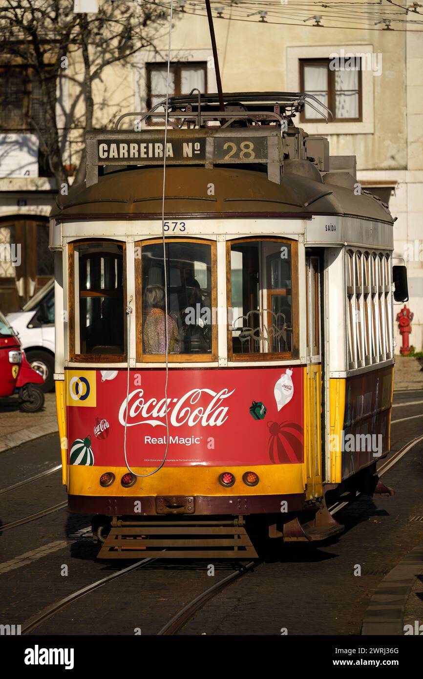 Straßenbahn 28 an einem sonnigen Nachmittag durch die historischen Straßen von Lissabon, Portugal. Februar 2024. Stockfoto