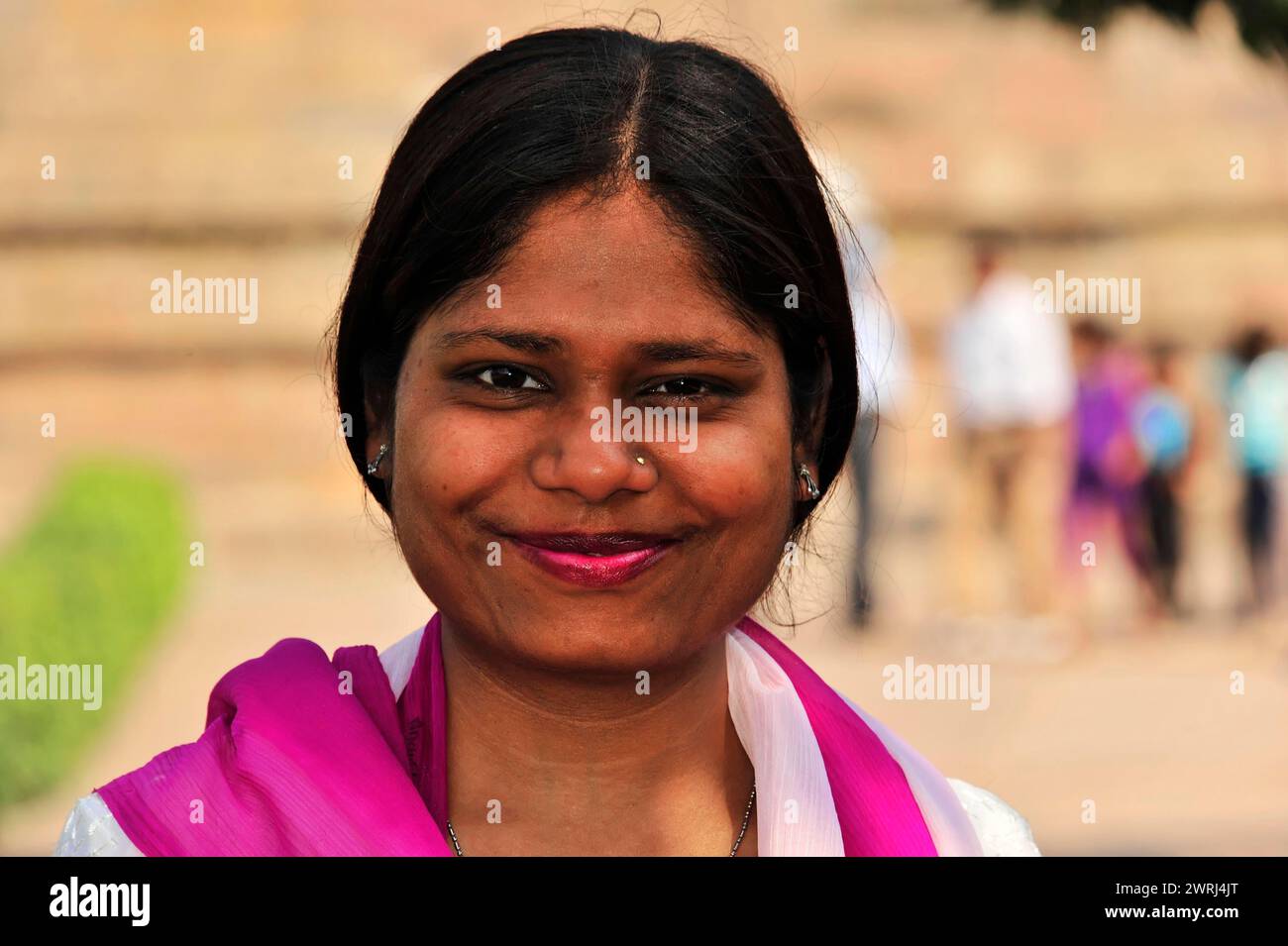 Freundliche lächelnde Frau in lila Kleidung mit weißem Haarband, Varanasi, Uttar Pradesh, Indien Stockfoto