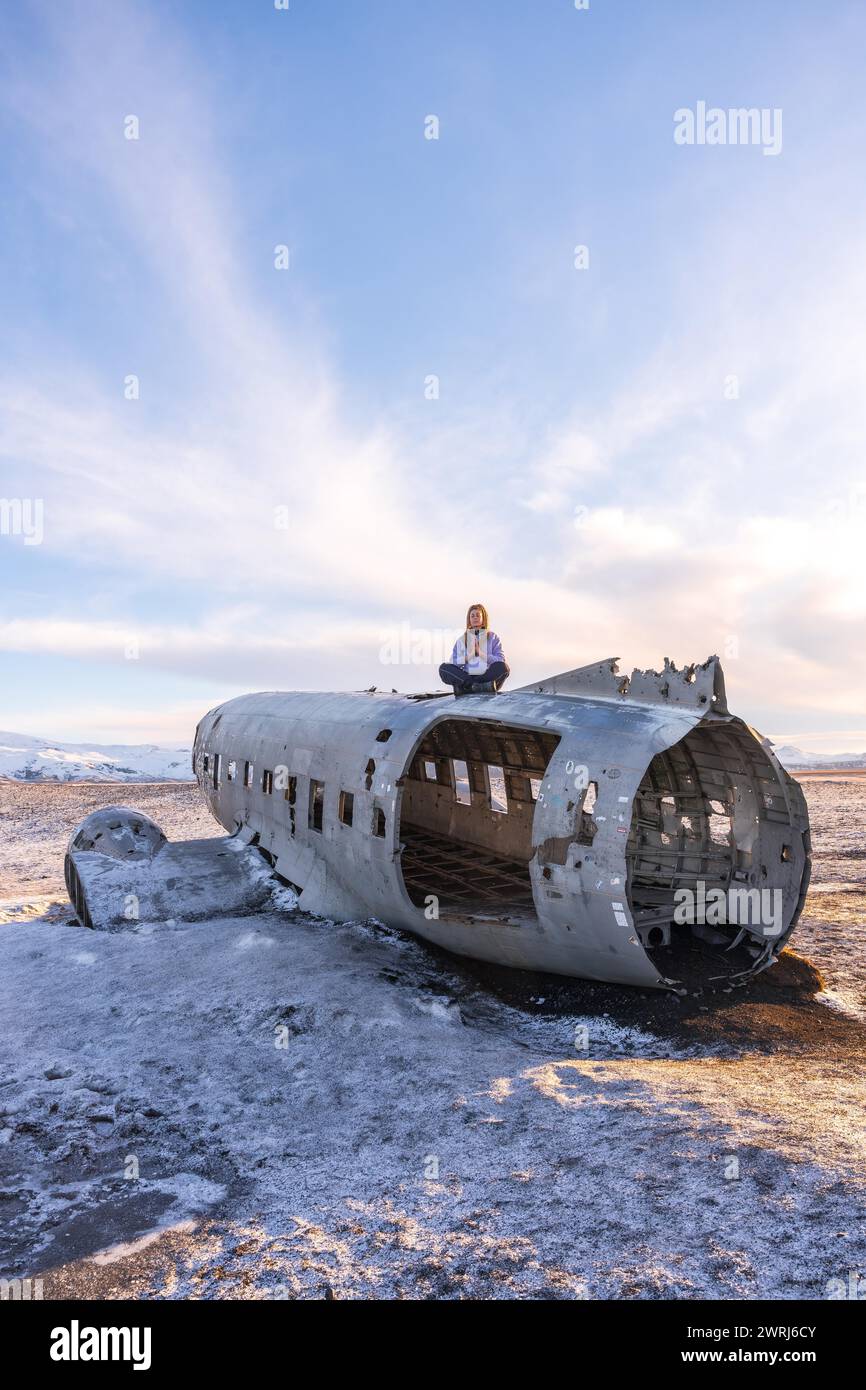 Frau, die auf dem Flugzeug von Solheimasandur sitzt, konzentrierte sich auf Meditation in Island Stockfoto