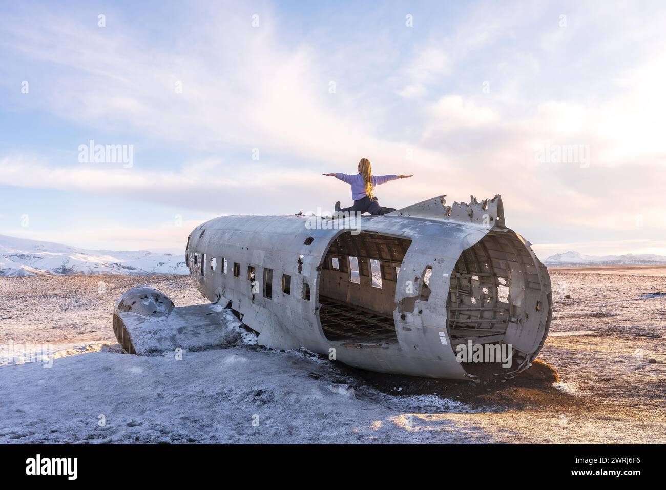 Frau, die auf dem Flugzeug von Solheimasandur sitzt, mit offenen Armen in der Meditation in Island Stockfoto