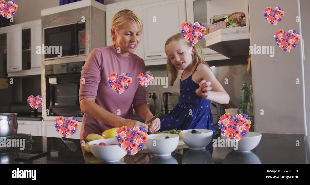 Bild von Blumenherzen über kaukasischer Mutter und Tochter, die zusammen kochen Stockfoto