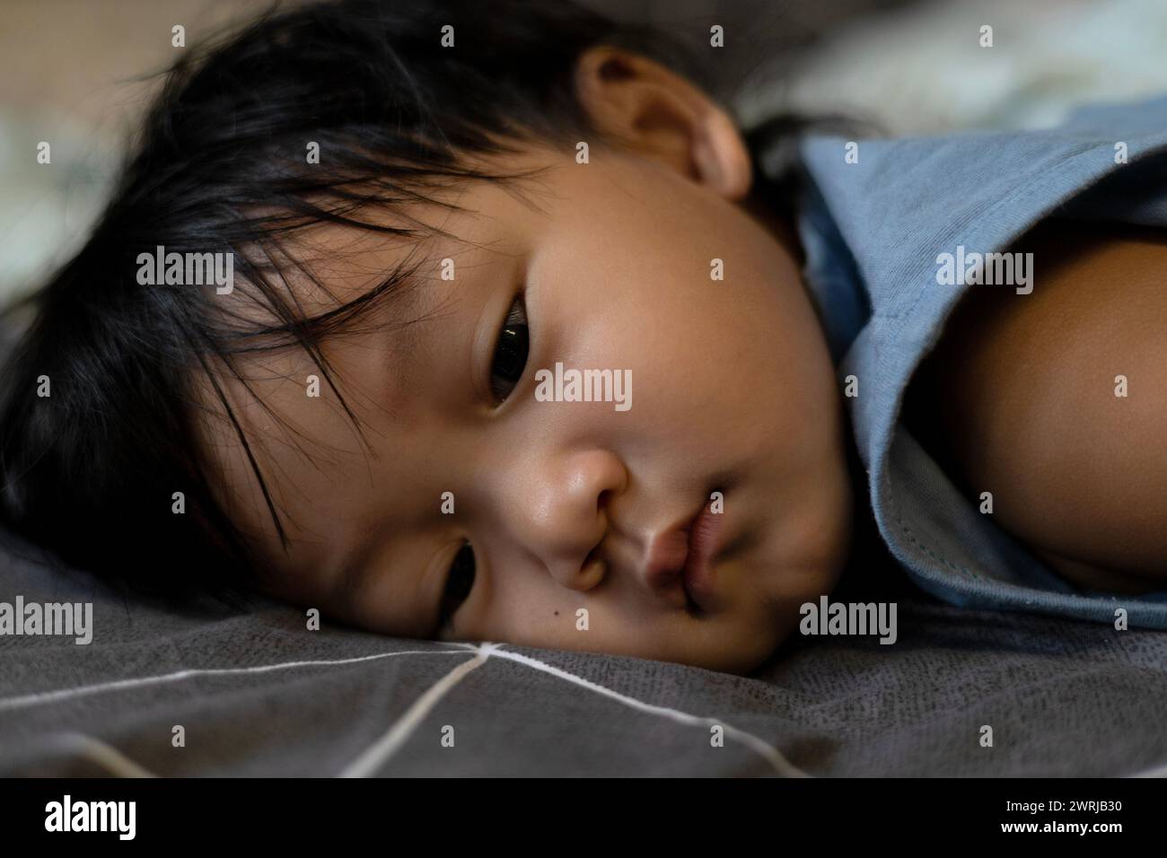 Der kleine Junge lag auf dem Bett und schlief ein, schlief ein oder schlief ein oder traurig. Stockfoto