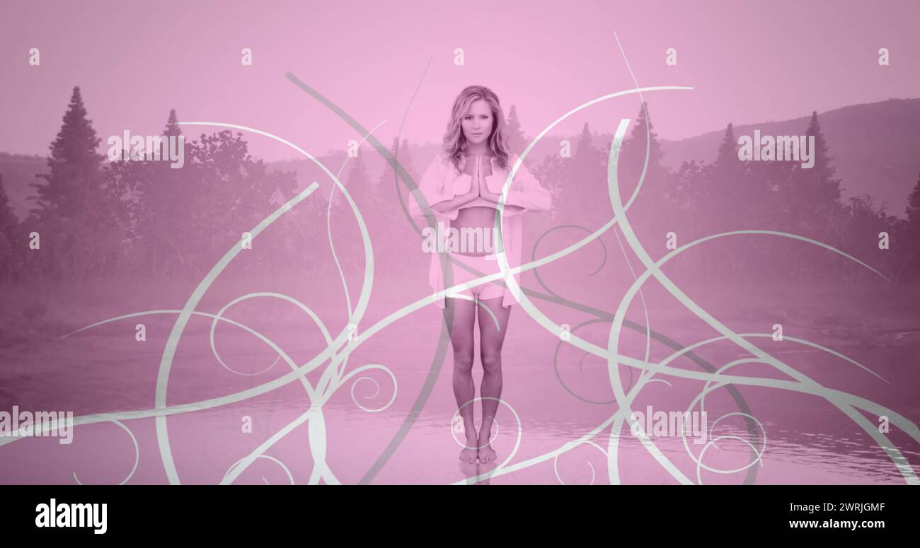 Vorderansicht einer kaukasischen Frau, die Yoga auf einem Hintergrund von Bäumen macht Stockfoto