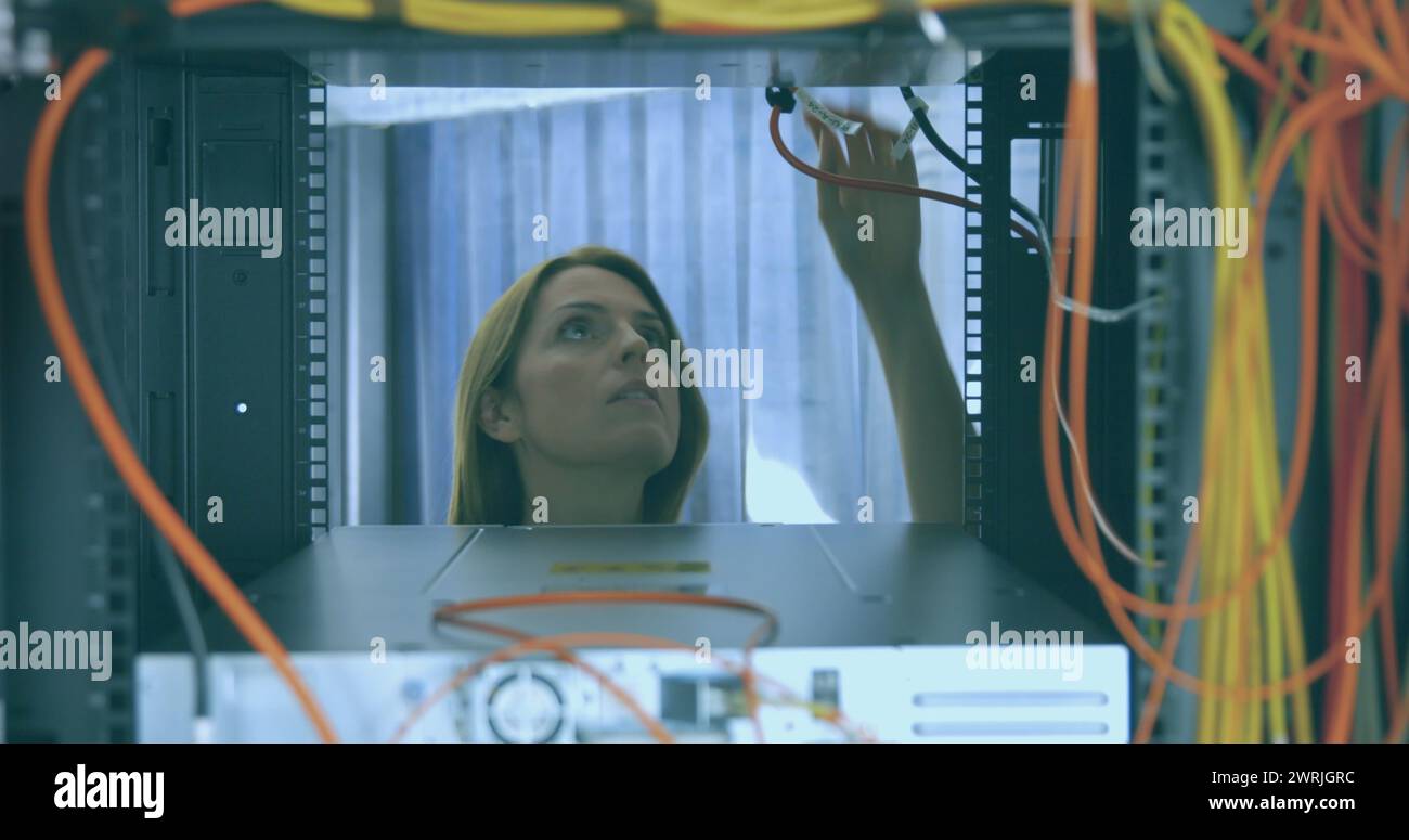 Eine Kaukasierin untersucht Serverkabel in einem Rechenzentrum Stockfoto