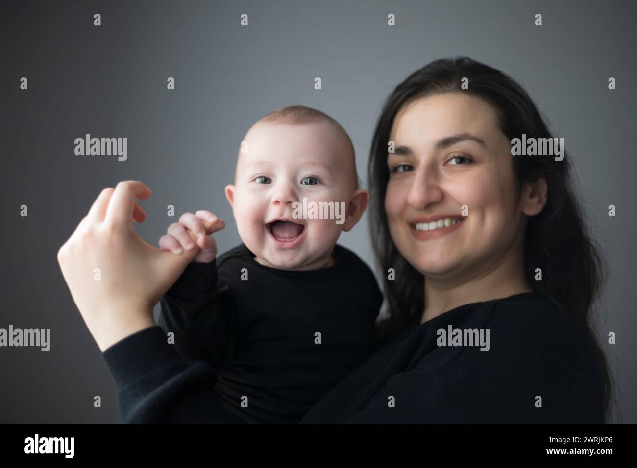 Glückliches, junges, lächelndes Mädchen in den Armen ihrer Mutter Stockfoto