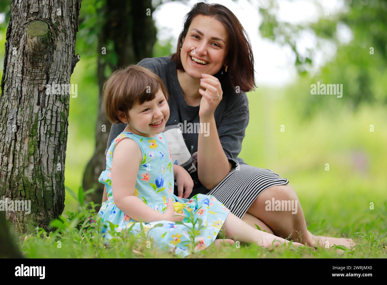 Mutter Tochter sitzt unter dem Baum Stockfoto