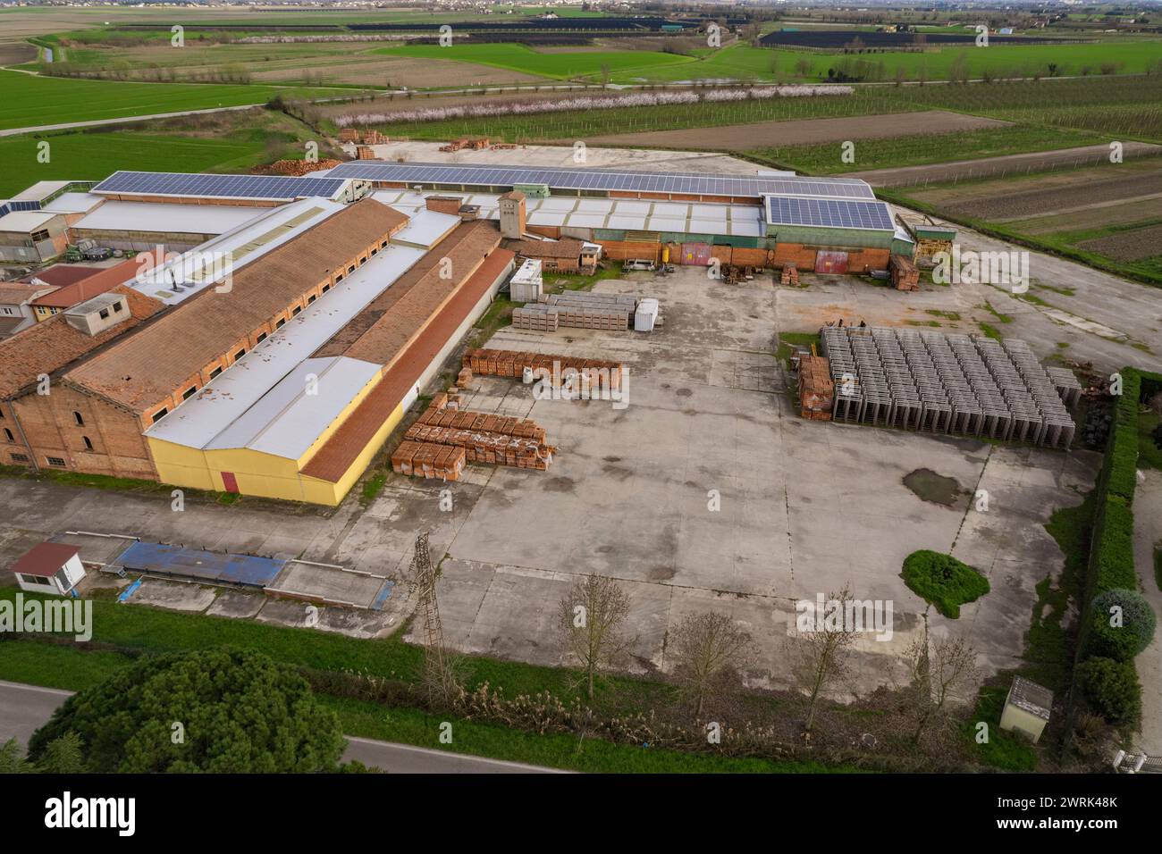 Die Luftaufnahme zeigt ein Industriegebäude in der flachen Ebene von Pianura Padana, in dem verschiedene Geräte und Maschinen in Betrieb sind. Die sce Stockfoto