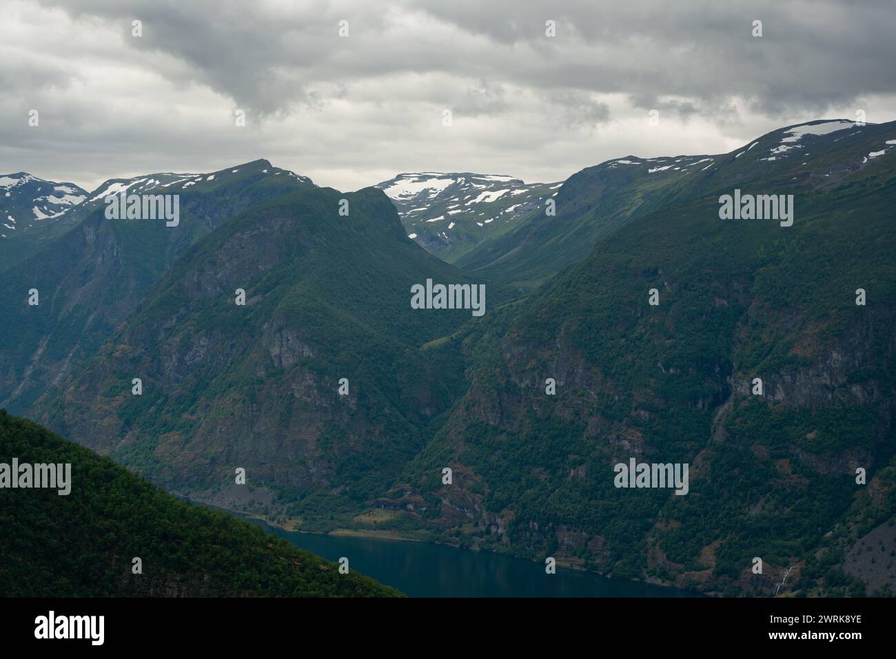 Naturblick auf die norwegischen Berge mit weißer Schneedecke auf dem hohen Boden vom Stegastein-Aussichtspunkt an einem bewölkten Sommertag. Blaue uv-Strahlung auf dem Stockfoto