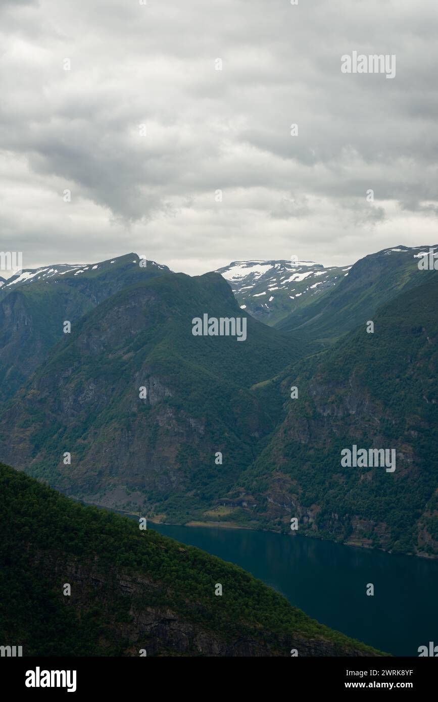 Naturblick auf die norwegischen Berge mit weißer Schneedecke auf dem hohen Boden vom Stegastein-Aussichtspunkt an einem bewölkten Sommertag. Blaue uv-Strahlung auf dem Stockfoto