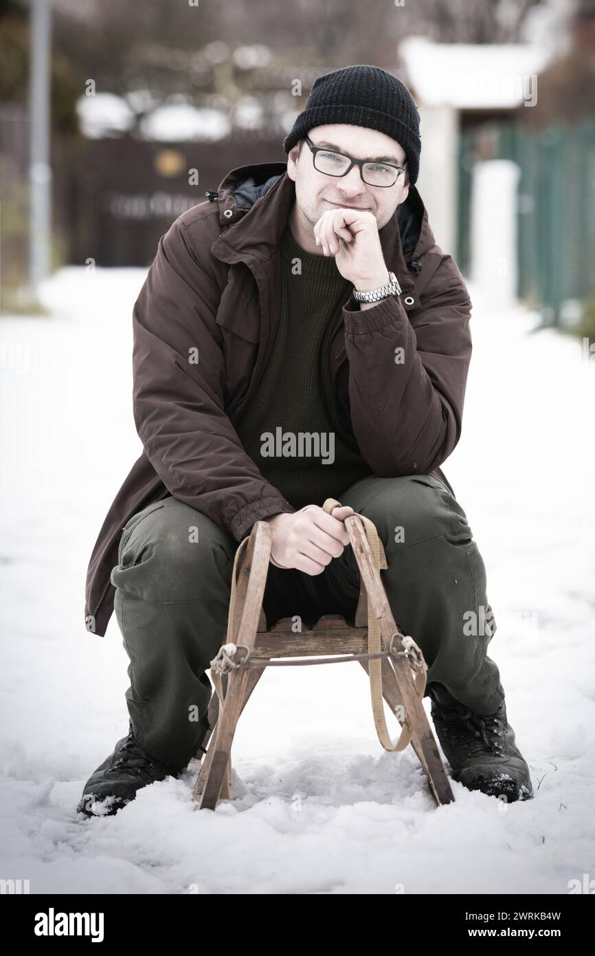 Erwachsener Mann, der den Winter mit klassischer Holzrodelbahn im Retro-Stil genießt Stockfoto