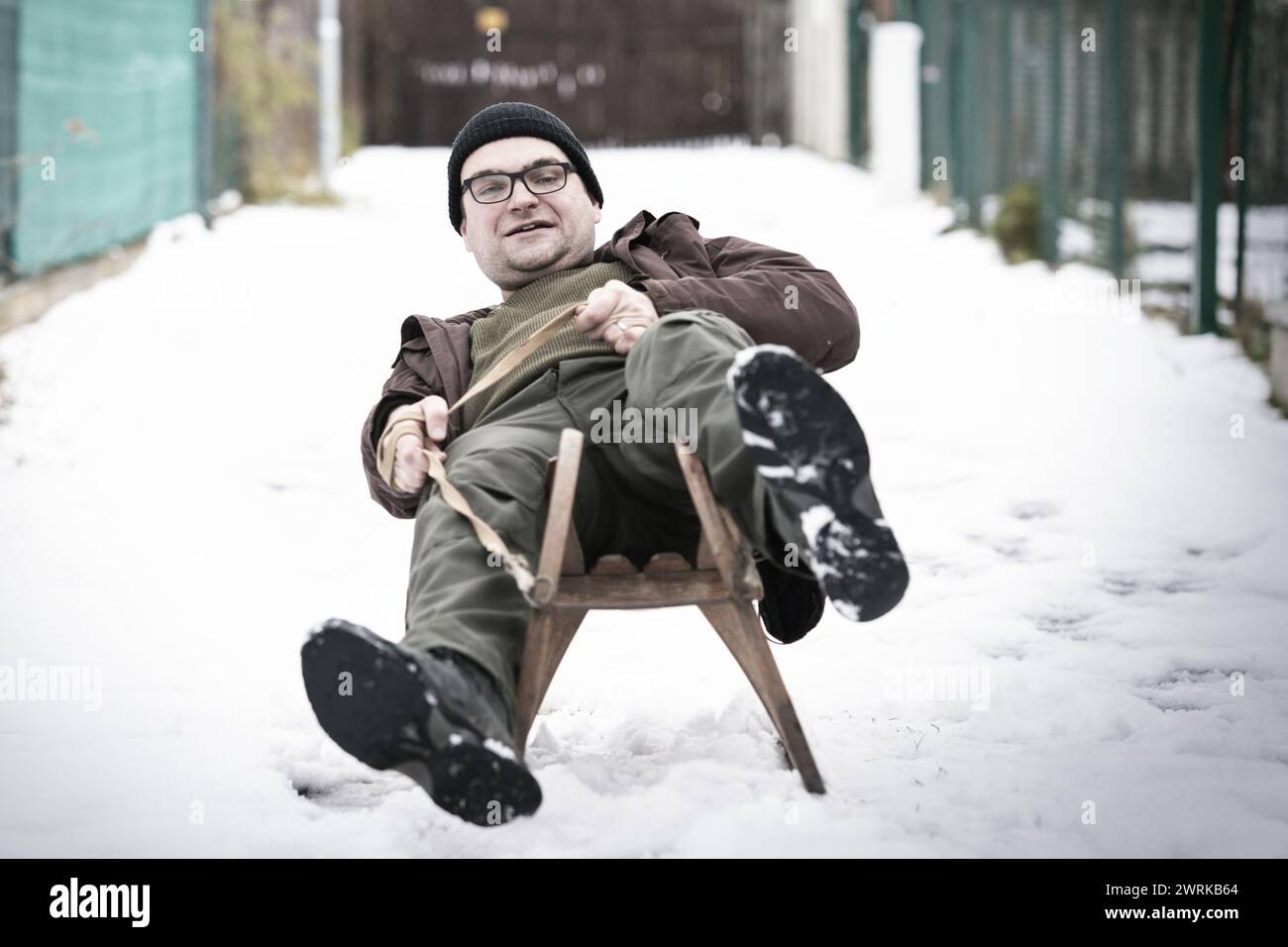 Erwachsener Mann, der den Winter mit klassischer Holzrodelbahn im Retro-Stil genießt Stockfoto
