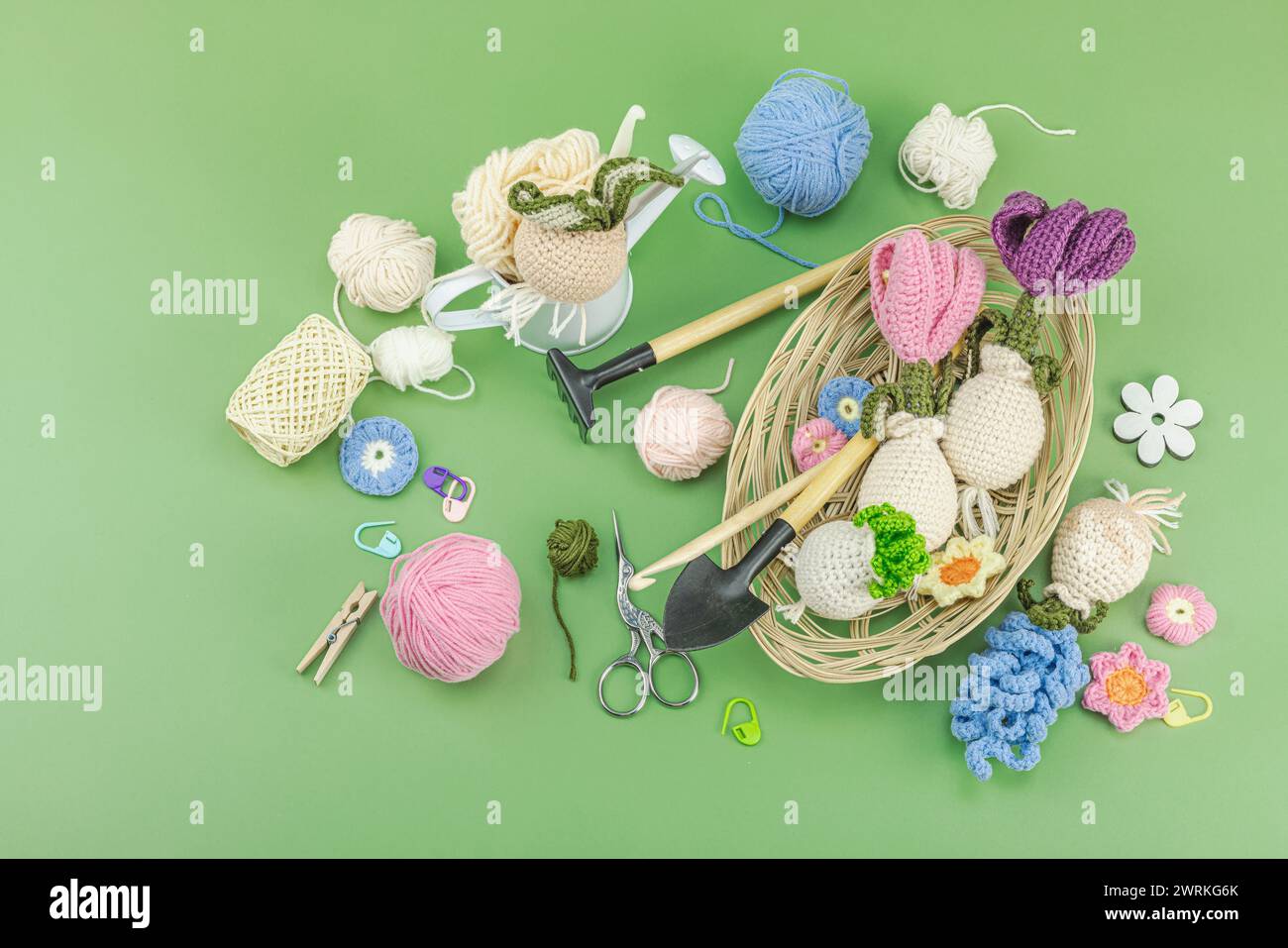 Frühjahrspflanz- und Gartenkonzept. Handgemachte Blumen mit Birnen, Miniwerkzeugen, Gießkanne und Eimern. Pastellgrüner Hintergrund, Draufsicht Stockfoto