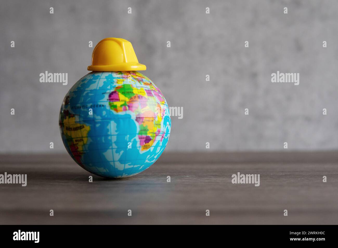 Schutzhelm auf der Weltkugel. Kopierbereich für Text. Arbeitstag, Konzept „Sicherheit an erster Stelle“. Stockfoto