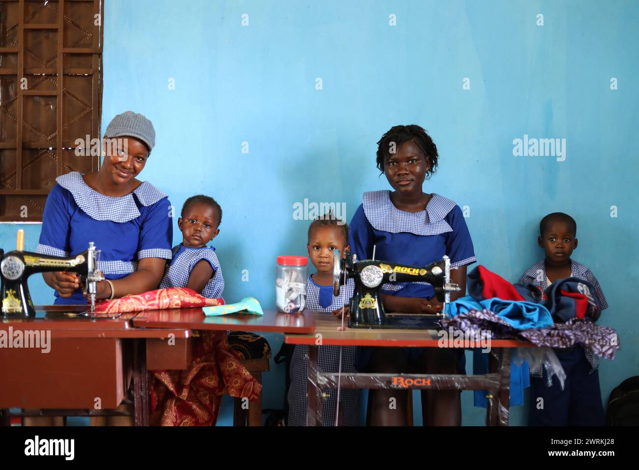 Frauen und Kinder stellten sich vor, wie sie bei der Muttervereinigung in Bo, Sierra Leone, Afrika, handwerklich Hemden bastelten. Stockfoto