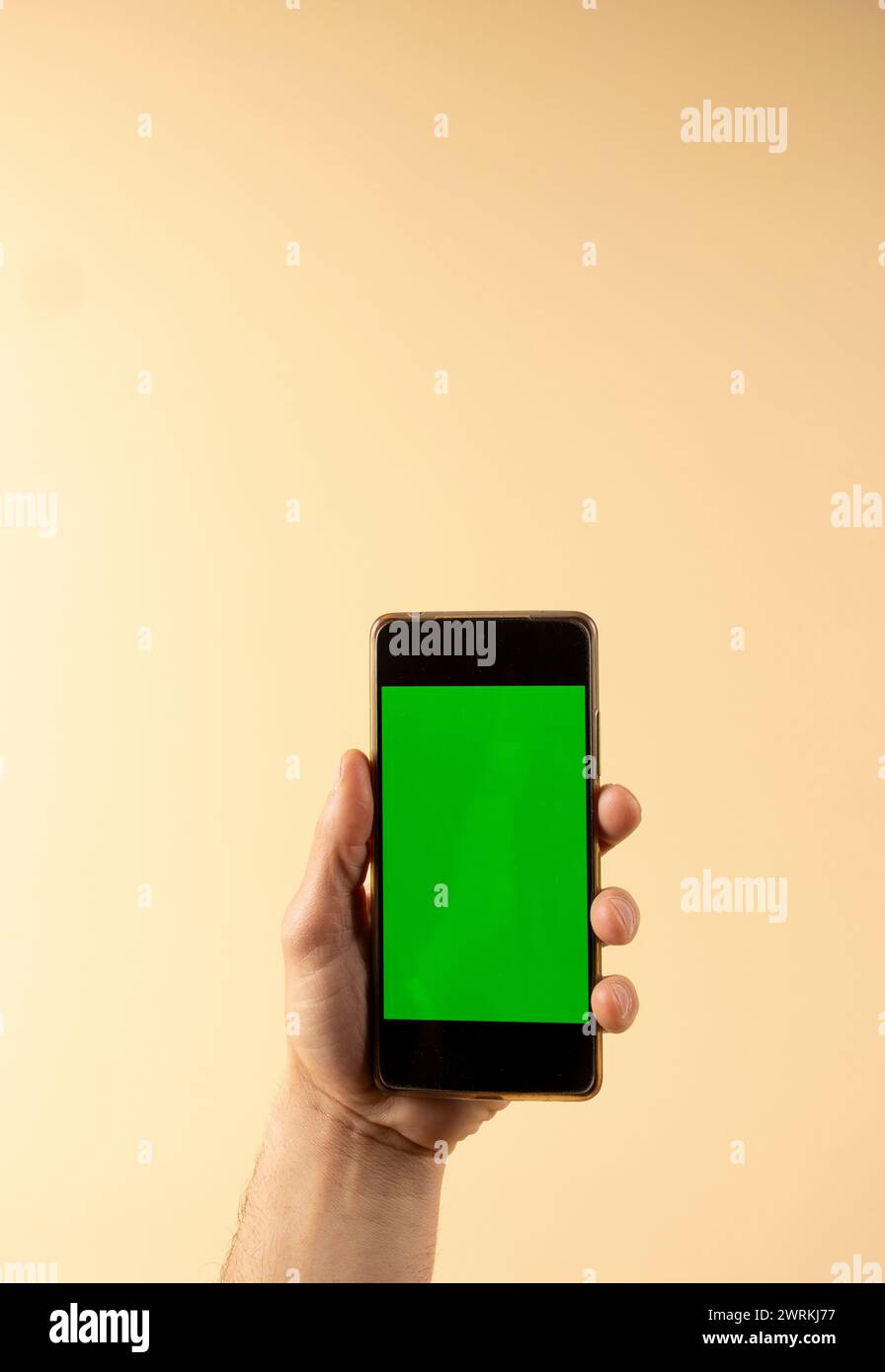 Handgriff-Smartphone mit grünem Bildschirm auf pastellfarbenem Hintergrund mit Kopierraum Stockfoto