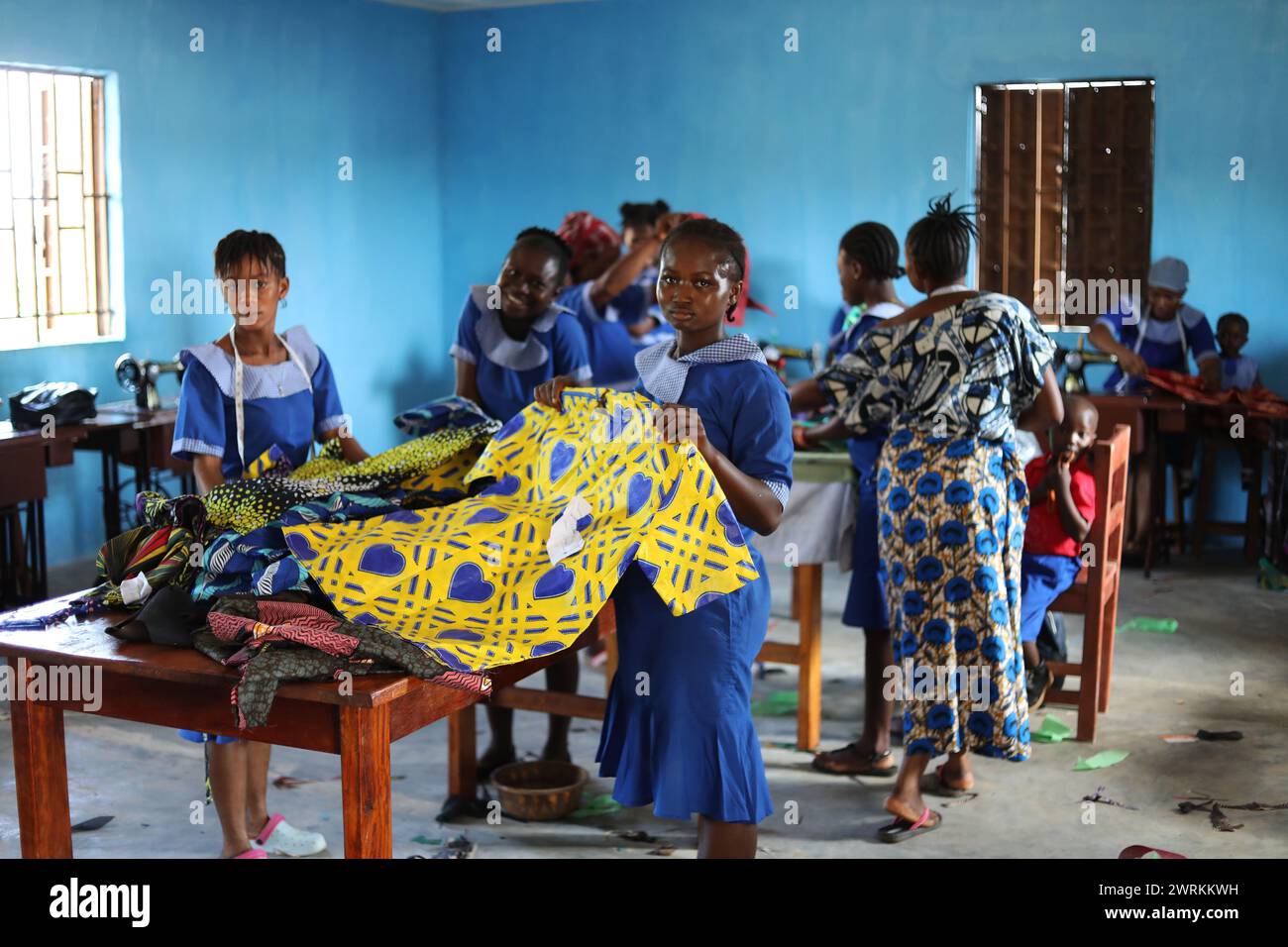 Frauen und Kinder stellten sich vor, wie sie bei der Muttervereinigung in Bo, Sierra Leone, Afrika, handwerklich Hemden bastelten. Stockfoto