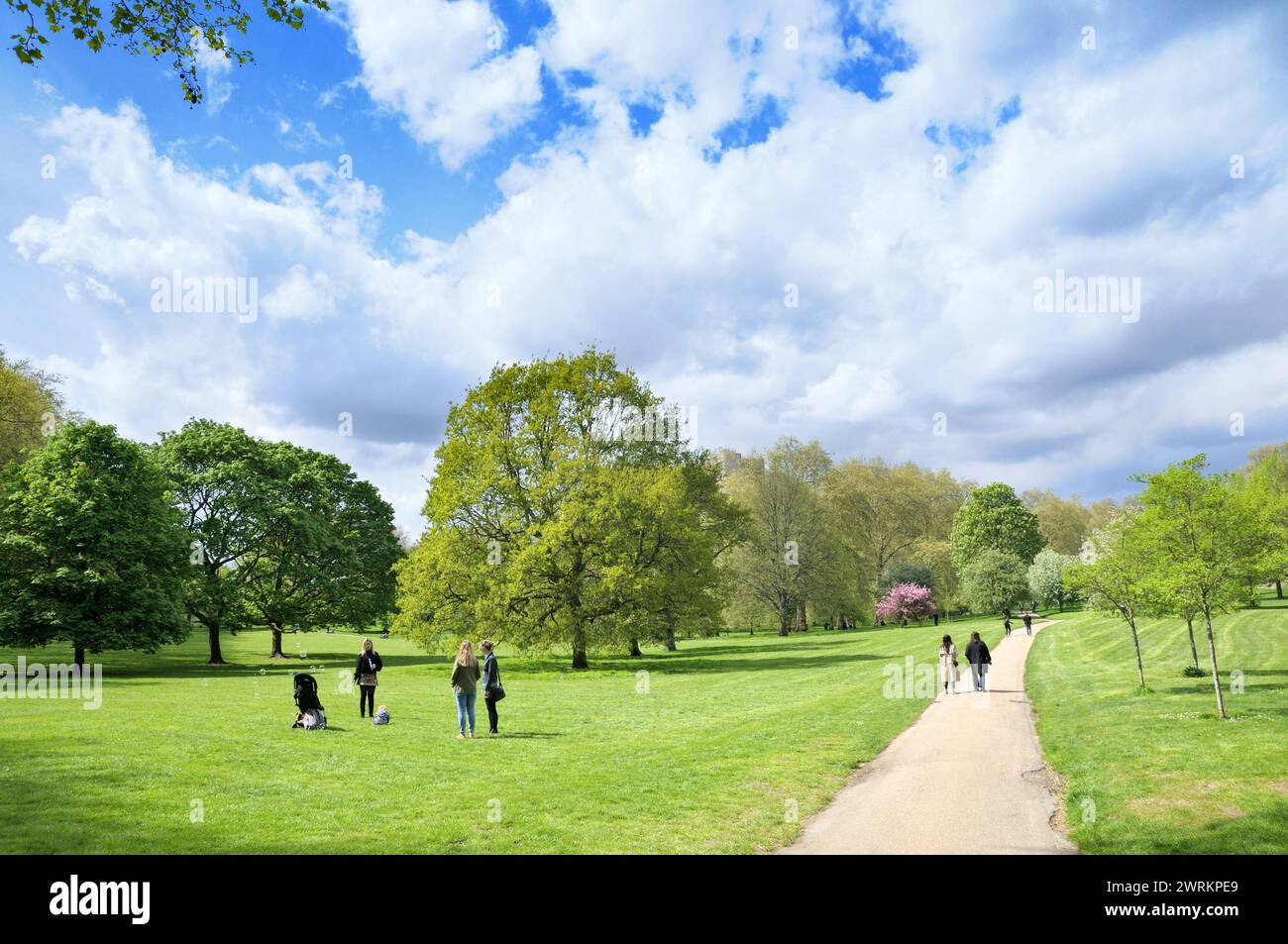Die Gäste entspannen sich und genießen die Frühlingssonne und die offene Fläche des Green Park, einer der acht Londoner Royal Parks im Zentrum von London, England, Großbritannien Stockfoto