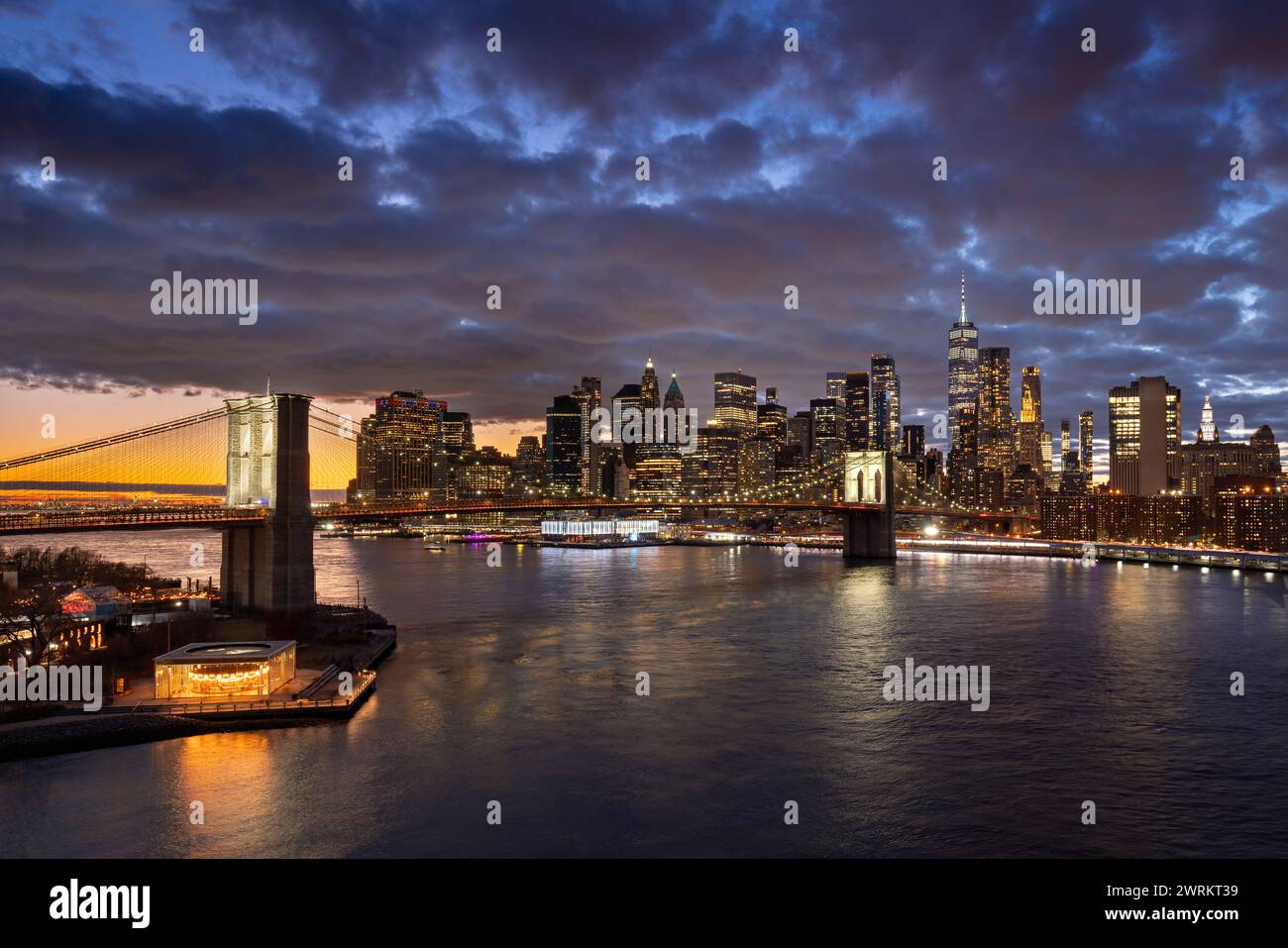 Brooklyn Bridge und Uferpromenade mit dem East River. Dumbo und Lower Manhattan beleuchtete Wolkenkratzer in der Dämmerung, New York City Stockfoto