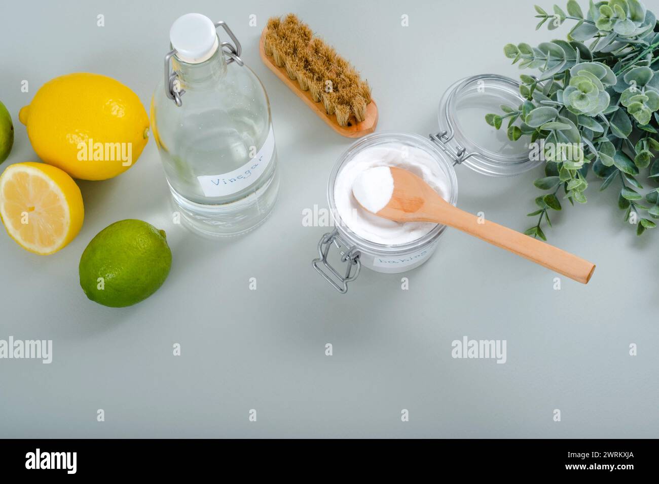 Natürliche Haushaltsreinigungsmittel Natron, Weißessig, Zitrusfrüchte, Pinsel auf grauem Hintergrund. Stockfoto
