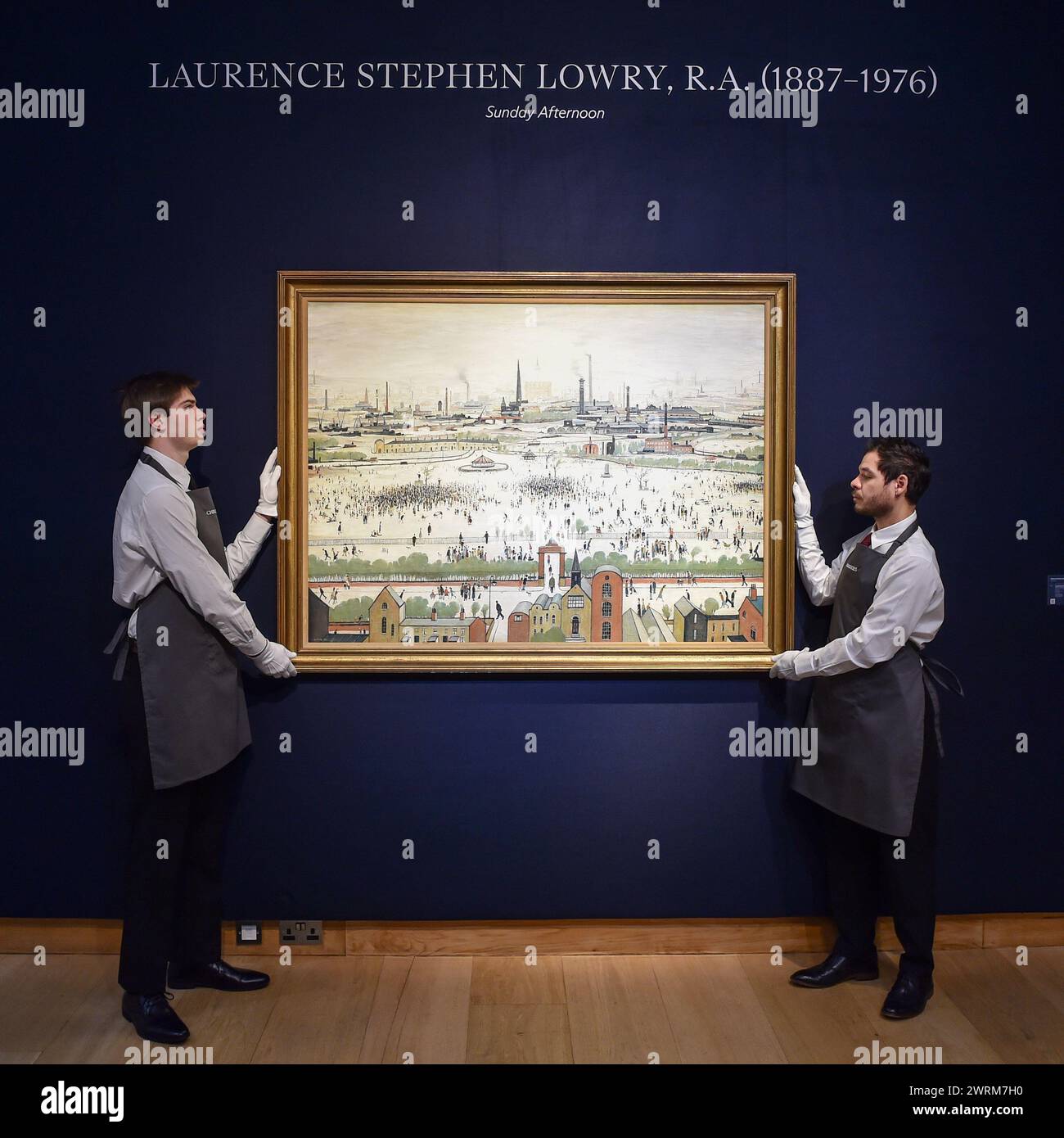 London, England, Großbritannien. März 2024. Christies Mitarbeiter halten L.S. Lowrys berühmtes Meisterwerk „Sunday Afternoon“ (1957), das nach 57 Jahren wieder in die Öffentlichkeit zurückkehrt. Dieses Gemälde wird am 20. März den Modern British and Irish Art Evening Sale im Christie's mit einem geschätzten Wert von 4.000.000 GBP bis 6.000.000 GBP führen. (Kreditbild: © Thomas Krych/ZUMA Press Wire) NUR REDAKTIONELLE VERWENDUNG! Nicht für kommerzielle ZWECKE! Stockfoto
