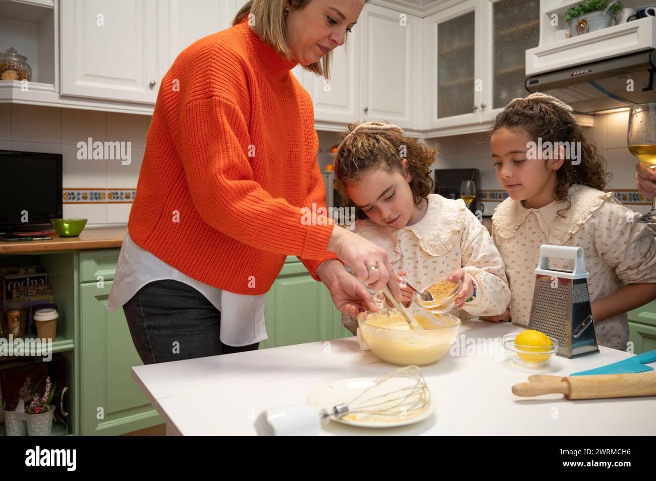 Ein warmer Familienmoment, in dem eine Mutter und ihre beiden Kinder zusammen in einer malerischen Küche backen und das Wesen eines Familientreffens festhalten. Stockfoto