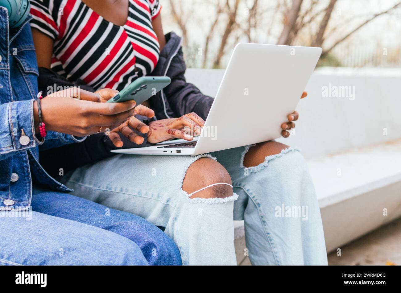 Ein fokussierter Blick auf zwei anonyme schwarze Schwestern, die sich mit Technologie beschäftigen und die Harmonie der digitalen Interaktion im Alltag demonstrieren Stockfoto
