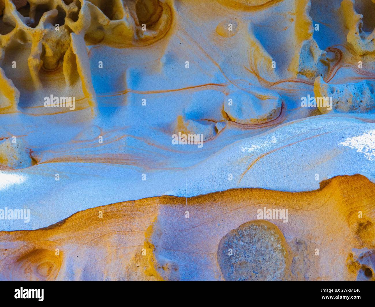Detaillierte Nahaufnahme der natürlich lebendigen und gemusterten Sandsteinklippen von Jaizkibel, die die geologische Schönheit und einzigartige Farbkombinationen zeigen Stockfoto