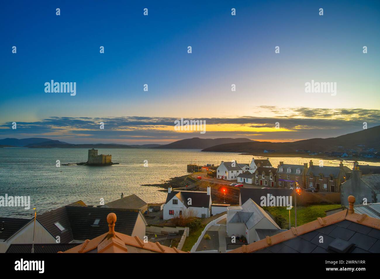 Blick auf den Sonnenuntergang über das Dorf Castlebay und Kisimul Castle, Isle of Barra, Äußere Hebriden, Schottland, Großbritannien Stockfoto